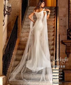 A woman in a lace wedding gown with tulle train stands on a stone staircase, facing away from the camera.