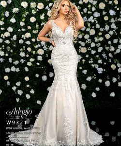 Woman wearing an embellished ivory mermaid gown stands in front of a wall decorated with white and yellow flowers.